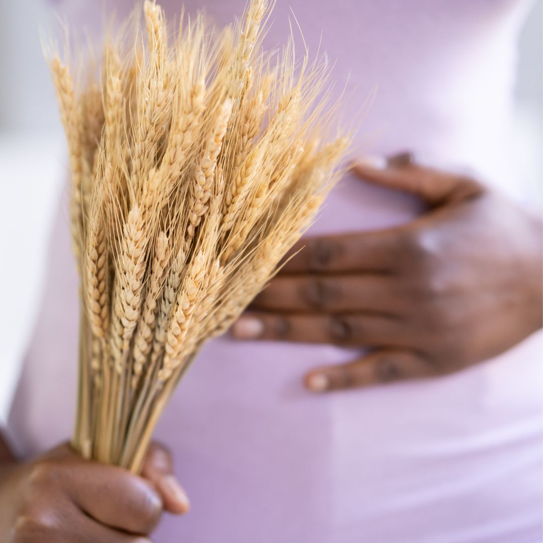 Femme tenant son ventre avec un bouquet de blé - Symptômes de la maladie cœliaque